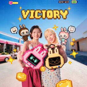 THE MONSTERS Shake A Drink Gaming Handheld in pink and gold, held up by two people